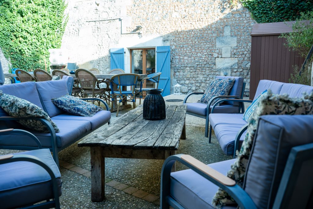 Terrasse conviviale de la maison d’hôtes et du gite Le Patio Bleu près d’Aubeterre en Charente, avec salon de jardin et murs en pierre couverts de lierre