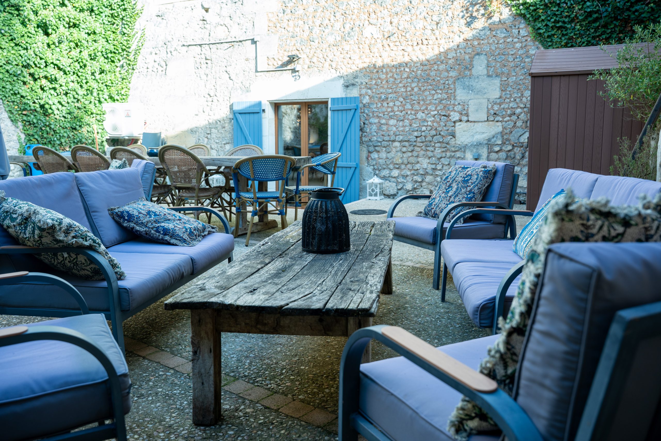 Terrasse conviviale de la maison d’hôtes et du gite Le Patio Bleu près d’Aubeterre en Charente, avec salon de jardin et murs en pierre couverts de lierre