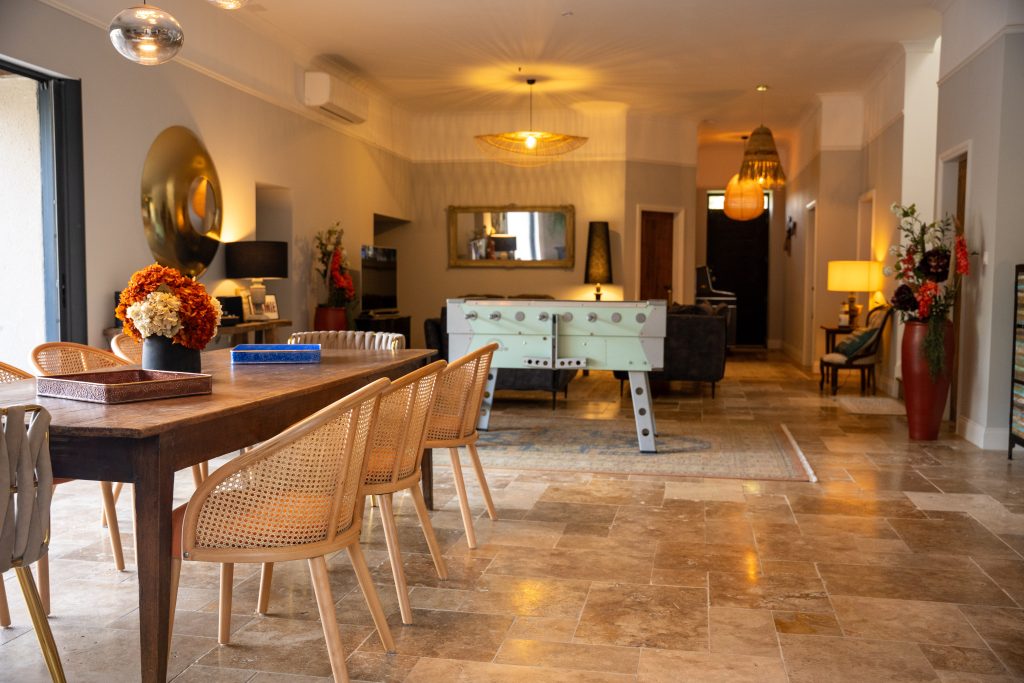 Salle commune de la maison d’hôtes Le Patio Bleu près d’Aubeterre en Charente, avec grande table en bois, baby‑foot et espace lounge convivial