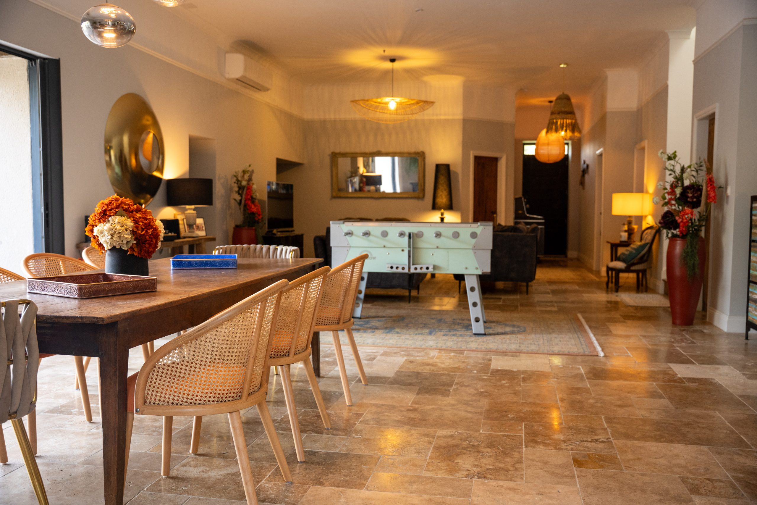 Salle commune de la maison d’hôtes Le Patio Bleu près d’Aubeterre en Charente, avec grande table en bois, baby‑foot et espace lounge convivial