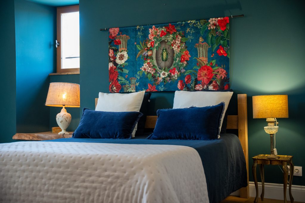Chambre double élégante de la maison d’hôtes Le Patio Bleu près d’Aubeterre en Charente, décorée en bleu profond avec coussins en velours et tenture florale
